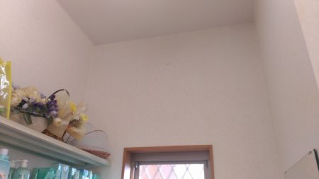 天井の隅と窓が見える室内、左側に花の飾りが置かれている