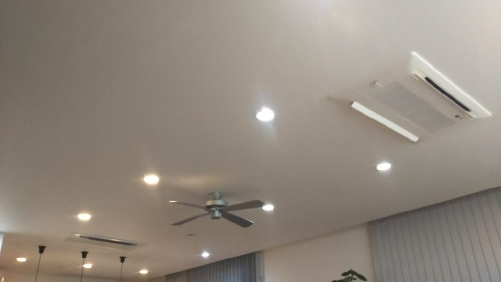 リビング天井のマルチエアコン取付部と天井扇風機、ダウンライトがある室内