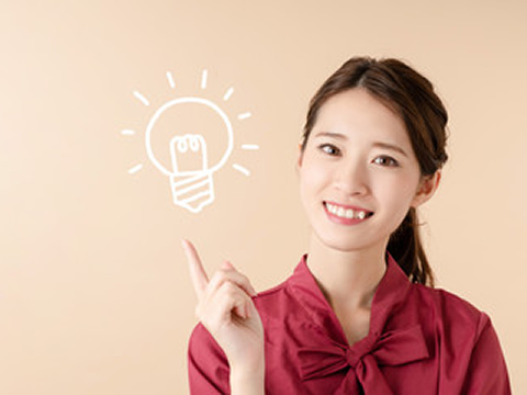 笑顔の女性が手を挙げ、光る電球のイラストを示している場面