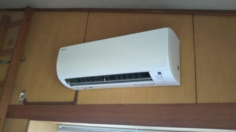 壁掛け型の家庭用エアコンが室内の木目の壁に設置されている様子。