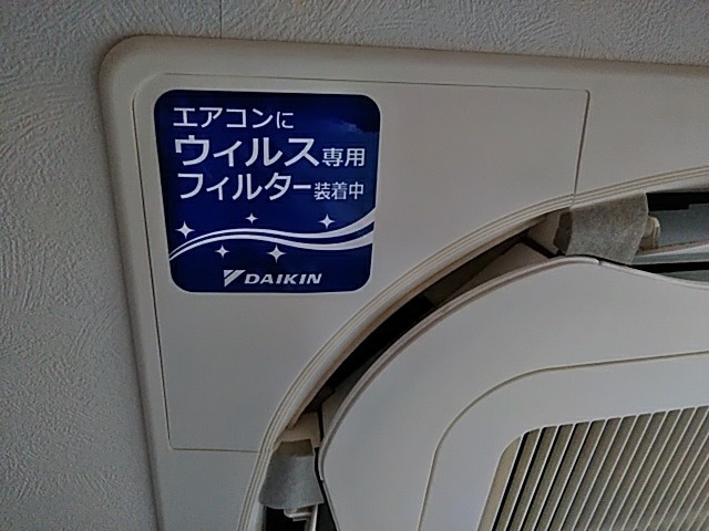 壁付けエアコンの外部ユニットに Daikin のウイルス専用フィルター装着を示すステッカーが貼られている画像